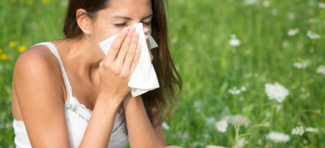picture of a woman blowing nose outside due to hayfever