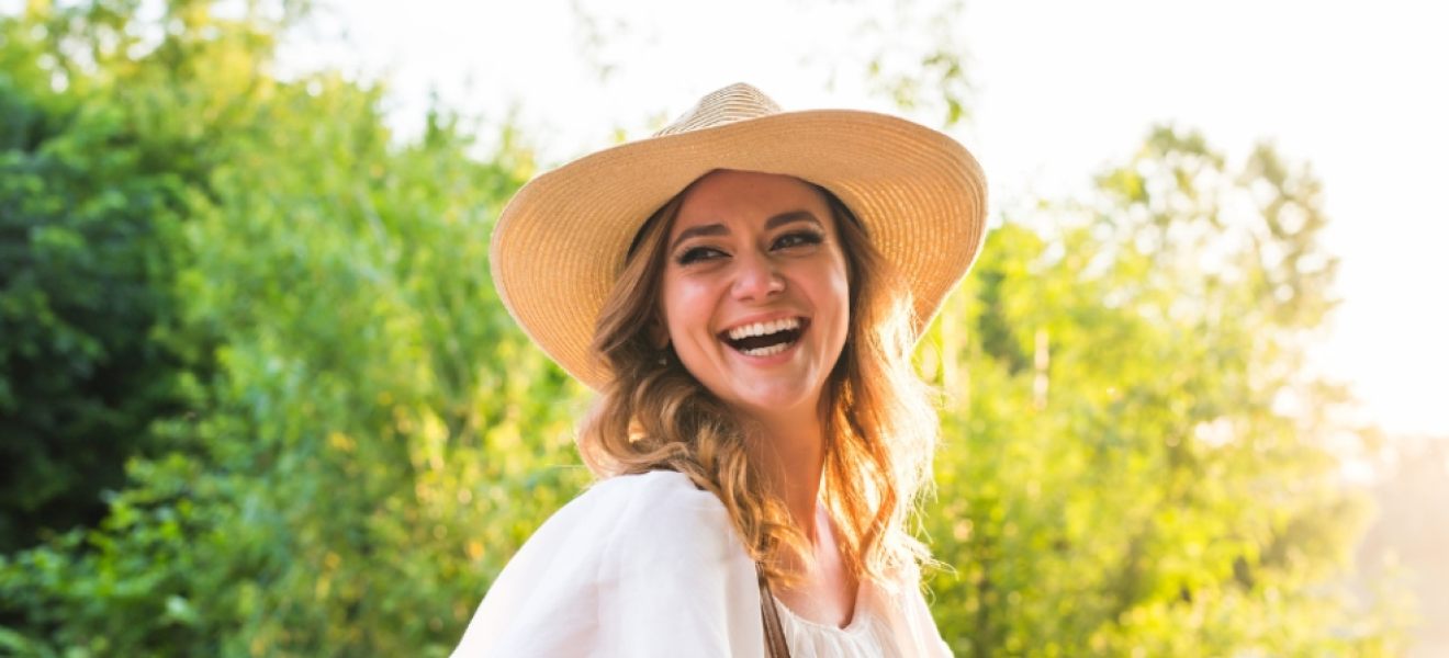 picture of a happy woman outside with nice hair wearing a hat for sun protection