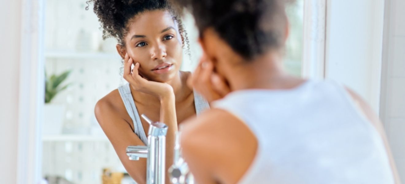 picture of a teenager doing a skincare routine looking in a mirror