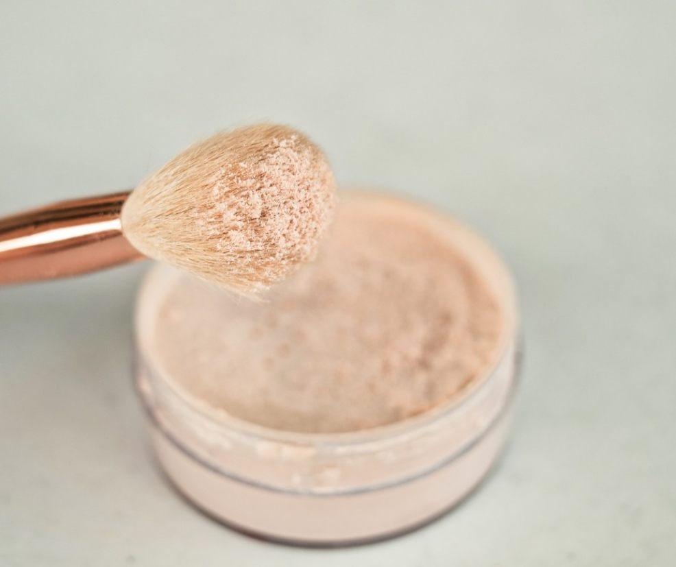 picture of a make up brush being dipped into a pop of setting powder
