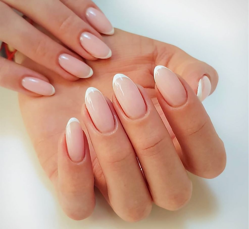 picture of a womans hand with french tip nail design