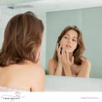 picture of a woman looking at her stressed skin in the mirror