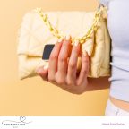 picture of a woman with pastel yellow nails holding a yellow handbag