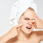 mage of a woman wearing a hair towel squeezing a face pimple.jpeg