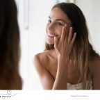 picture of a beautiful woman looking at her natural healthy skin in the mirror