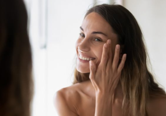 picture of a beautiful woman looking at her natural healthy skin in the mirror