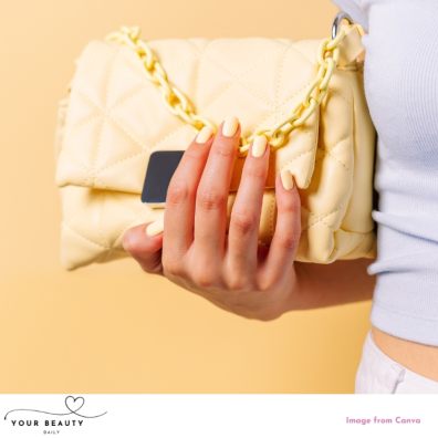 picture of a woman with pastel yellow nails holding a yellow handbag